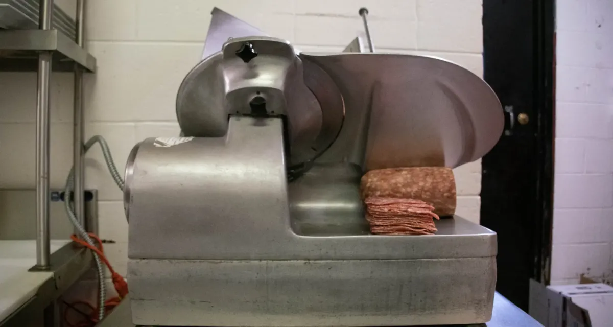 Commercial meat slicer used in a professional kitchen, highlighting food prep equipment serviced by SSI Services.
