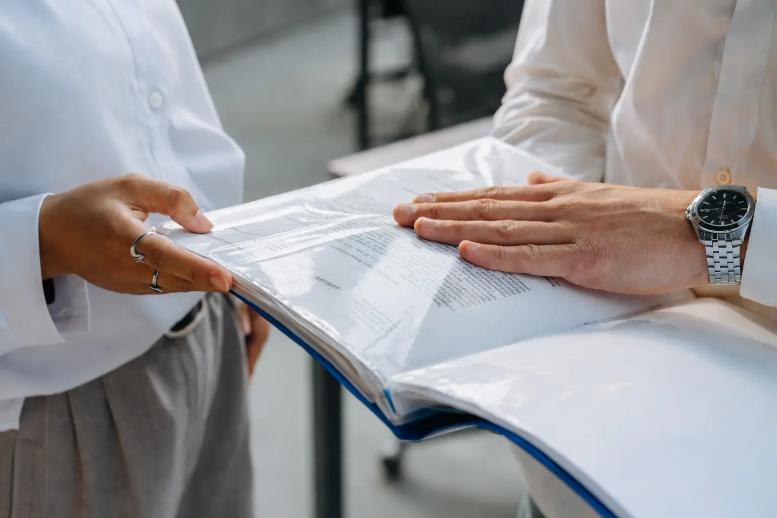 Hands reviewing organized equipment maintenance documents in a clear binder.